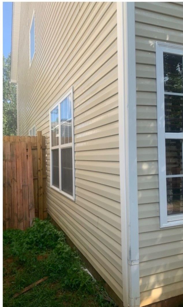 The side of a house with a wooden fence and a lot of windows.