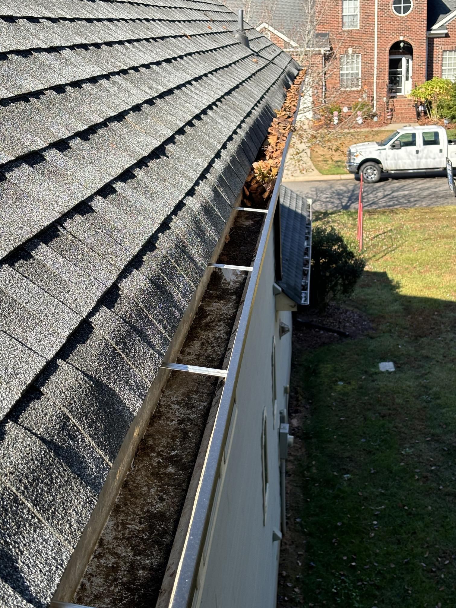 A gutter on the side of a house next to a roof.