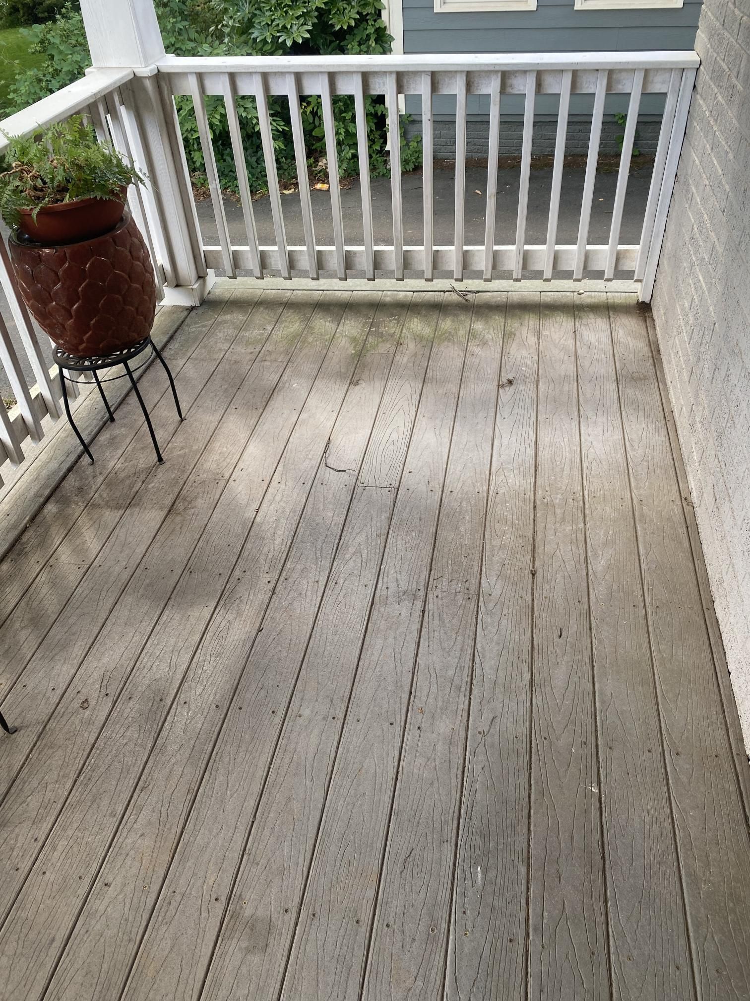 A wooden deck with a white railing and a potted plant on it.