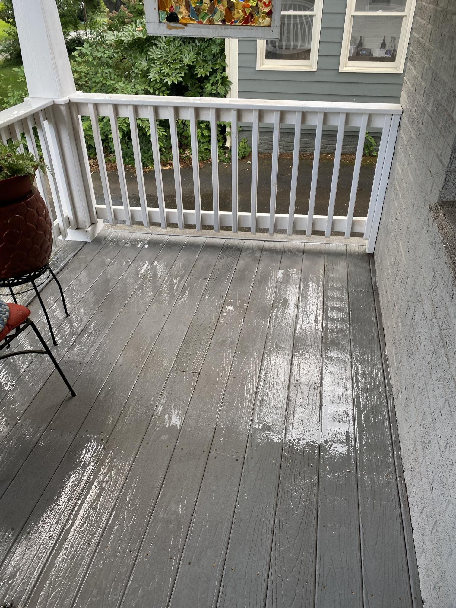 A porch with a white railing and a potted plant on it
