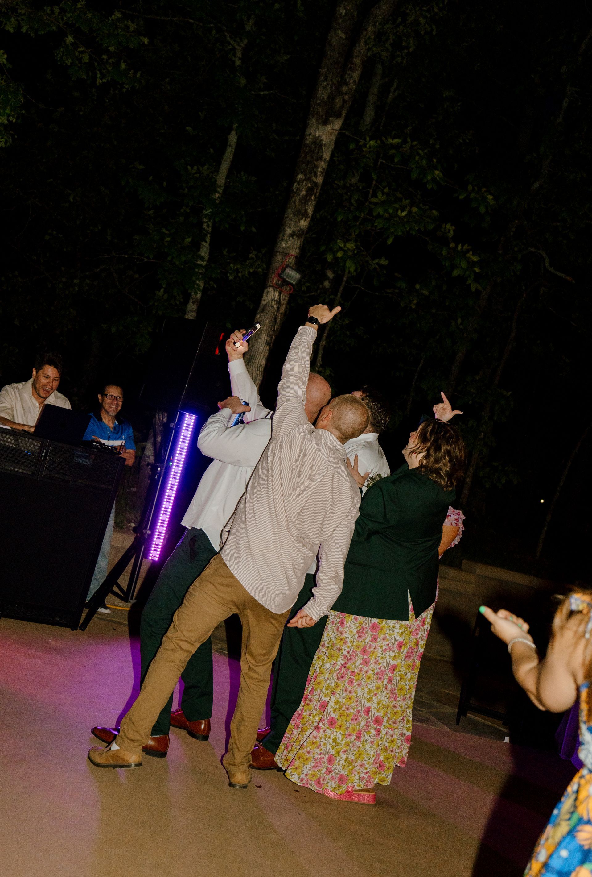 A group of people are having a party in a swimming pool. Bride and groom slow dancing under a pavilion at an outdoor wedding reception
