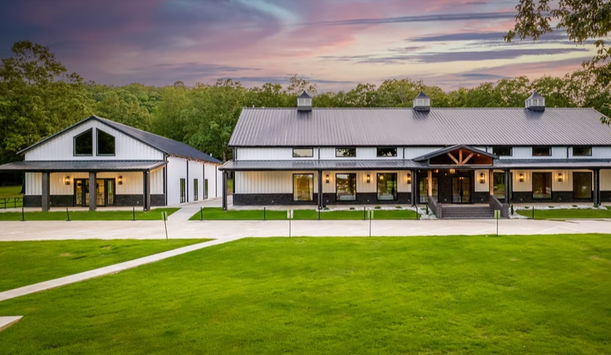 Modern white clubhouse with black roof on a green lawn at sunset
