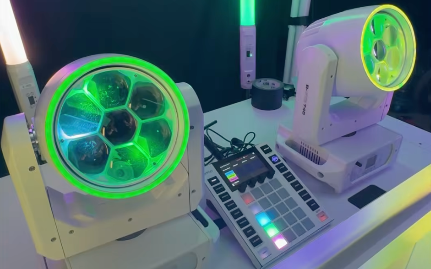 Two neon green-lit tower fans beside a small control panel on a desk, in a tech display setup