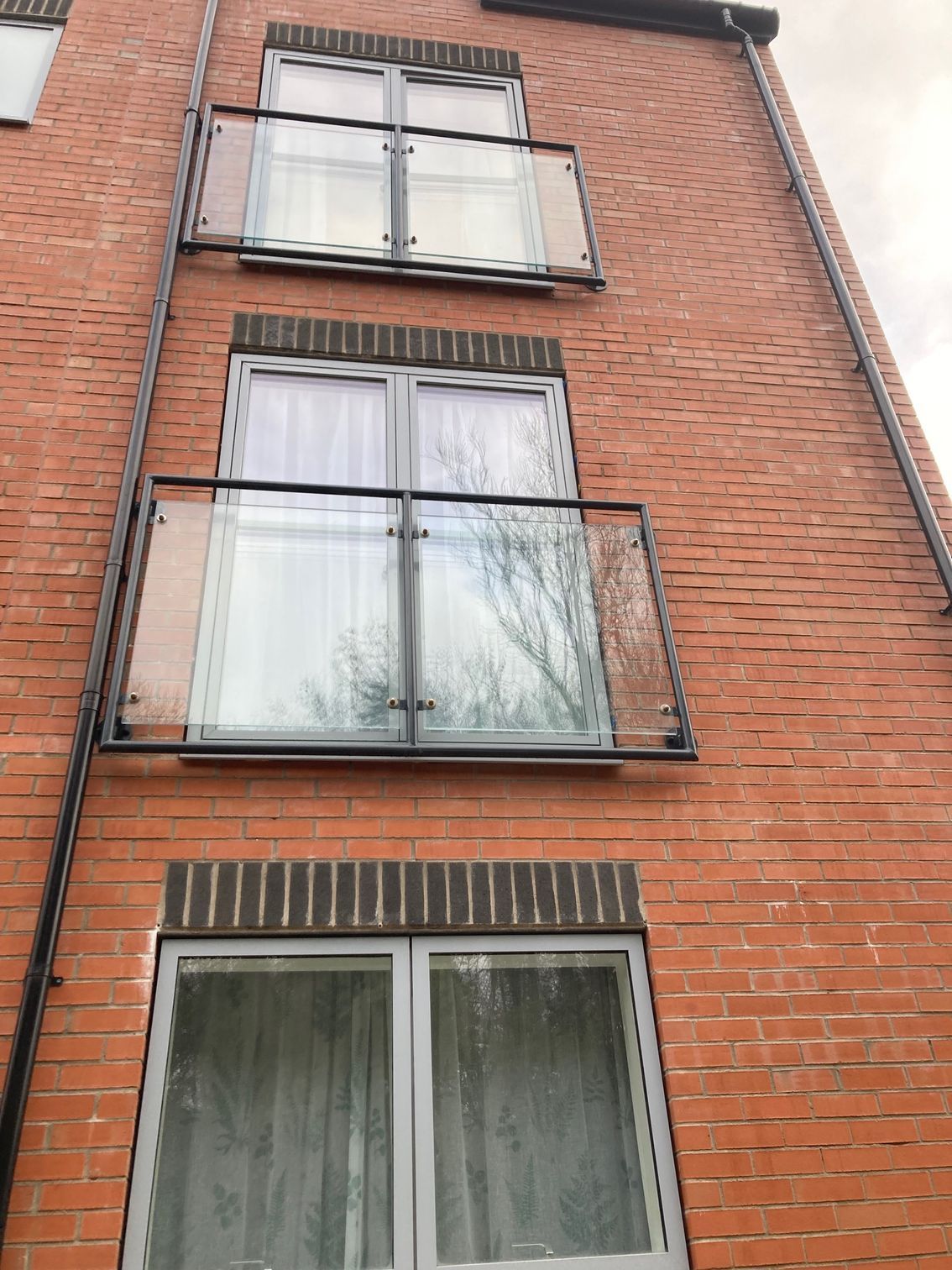 Brick building with three levels of windows, two with glass balconies.