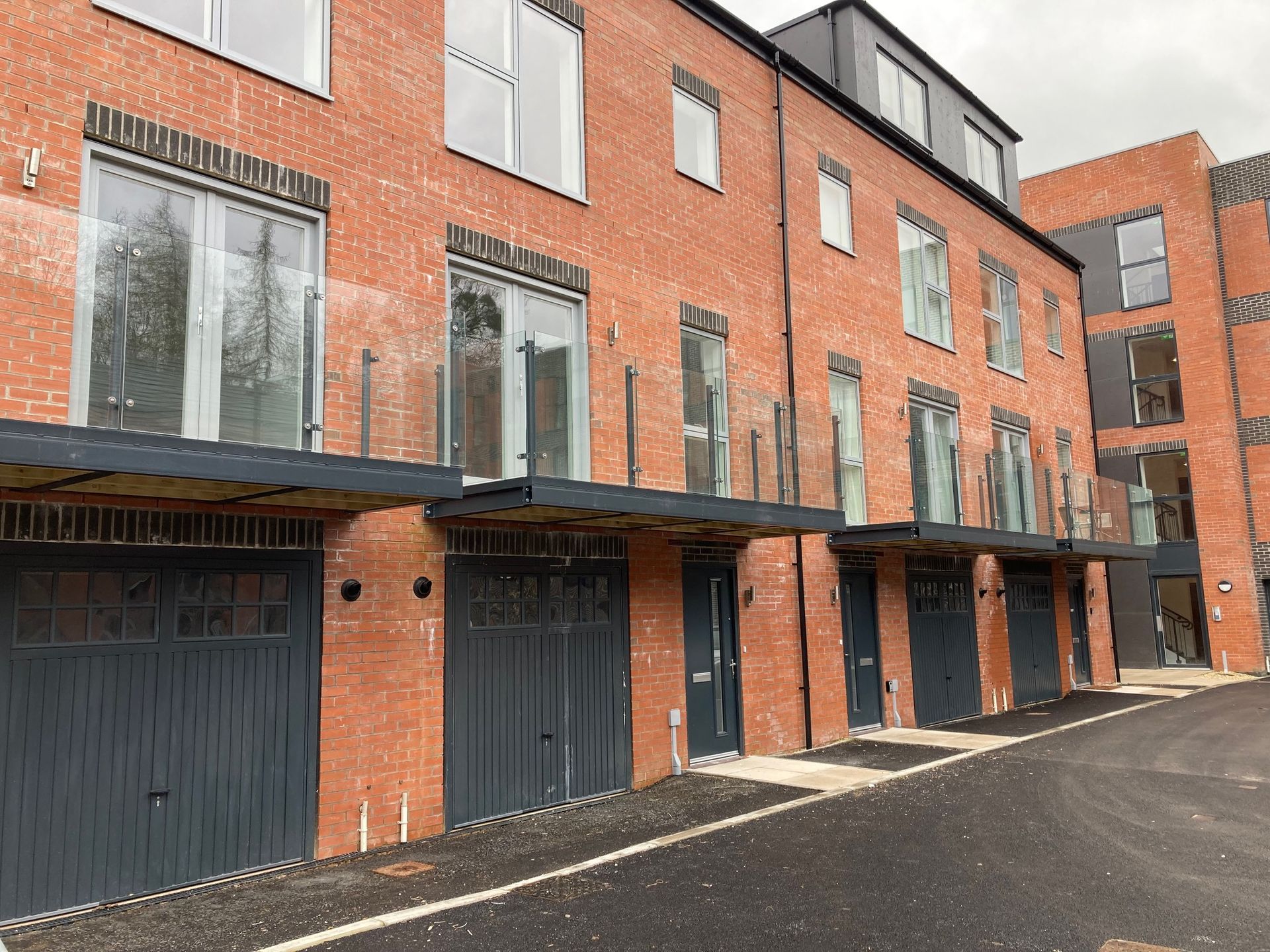 Brick townhouses with glass balconies over gray garage doors.