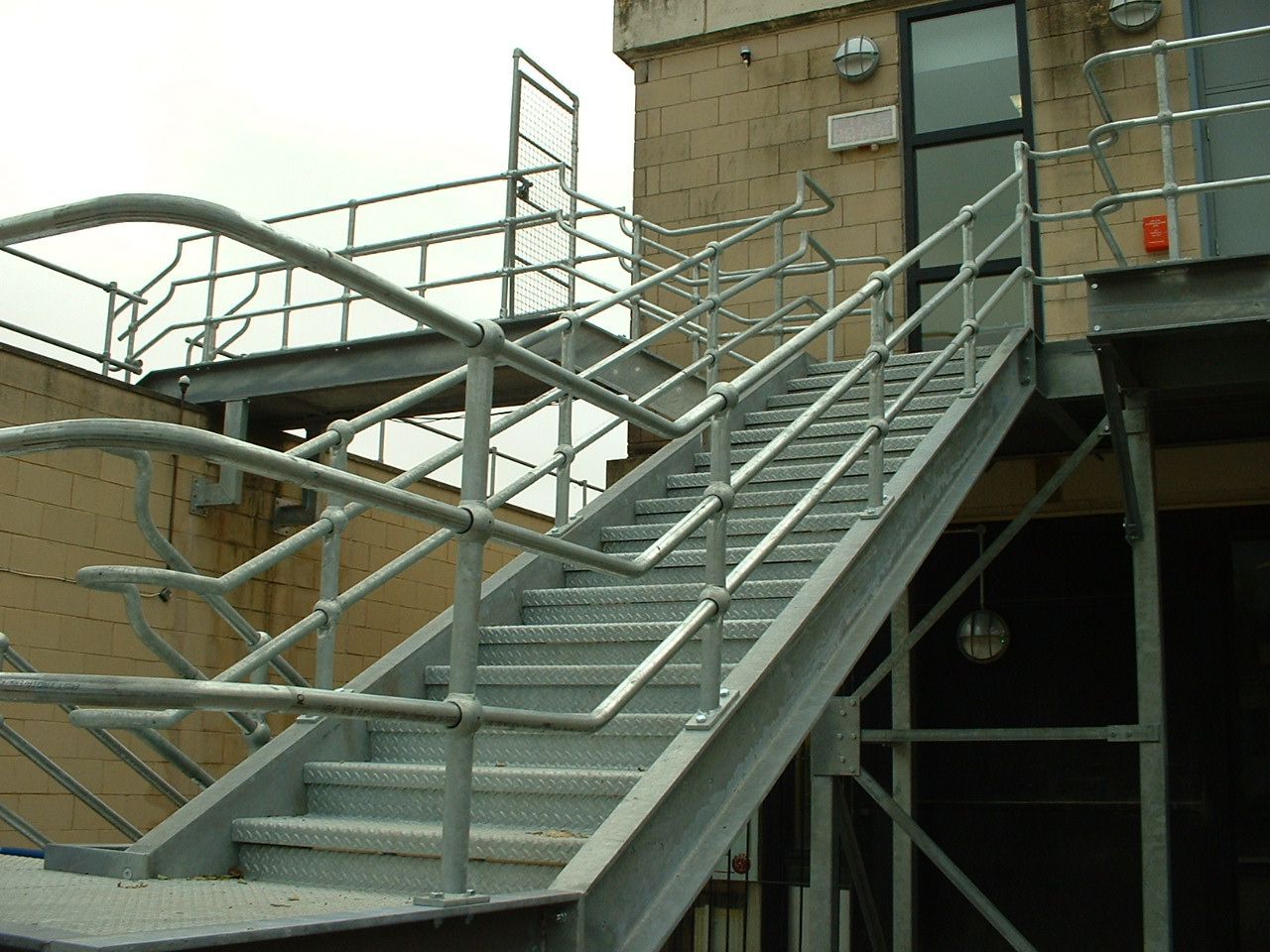 Exterior metal staircase leading to a building entrance with handrails.