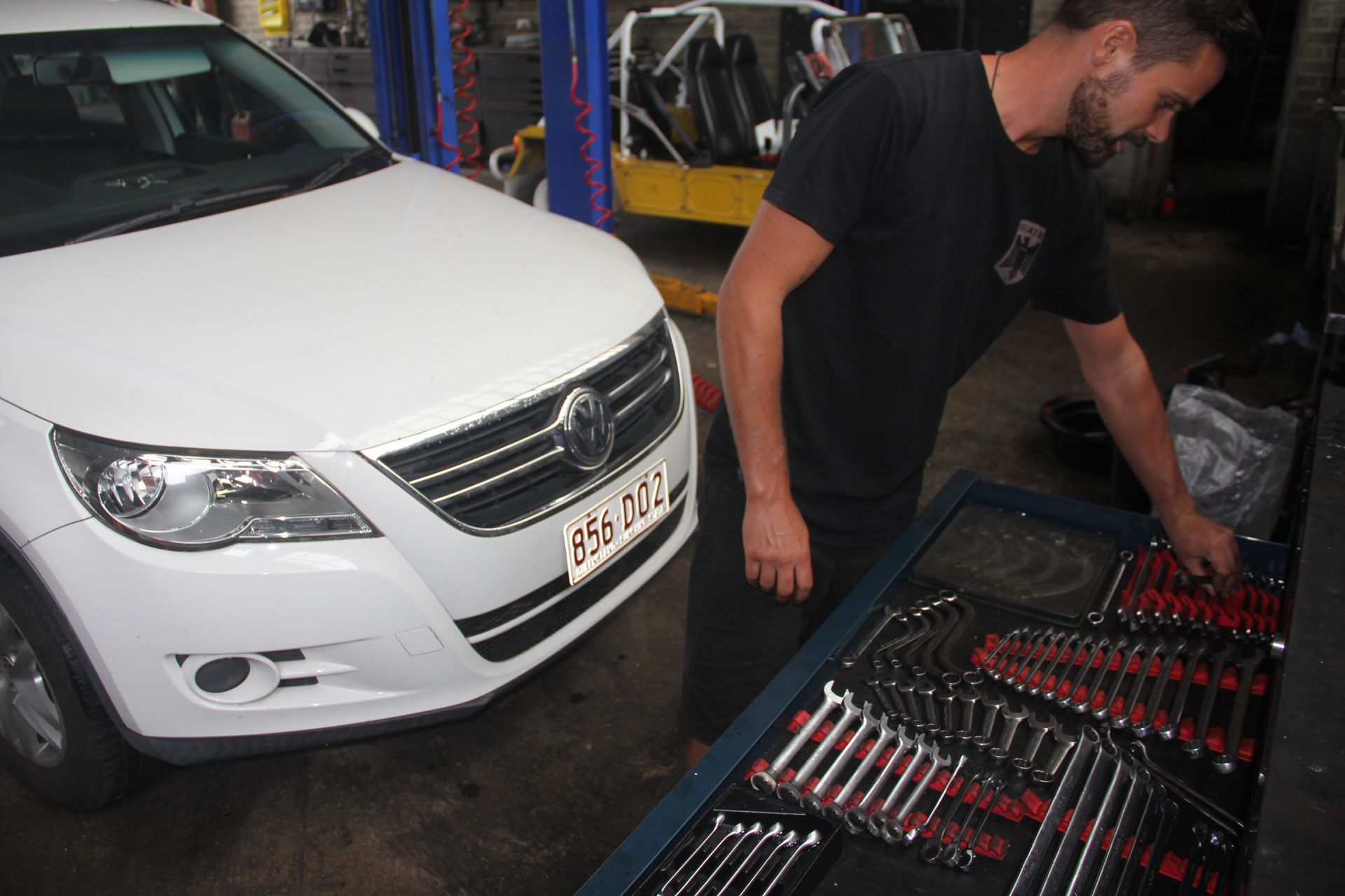A Man is looking at tray of car tools while working on VW— Stokers VW Mechanical Servicing & Repairs in Byron Bay, NSW