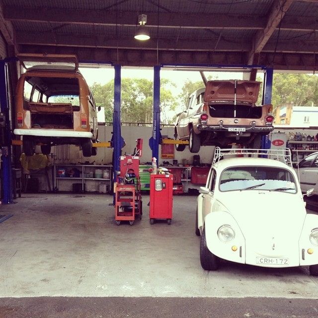 A Volkswagen Beetle is Parked in a Garage With Other Cars — Stokers VW Mechanical Servicing & Repairs in Byron Bay, NSW