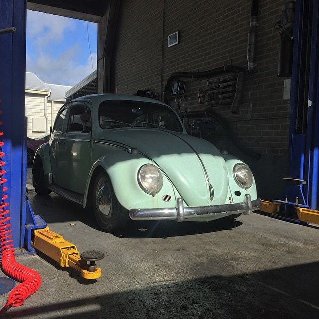 A Green Beetle is Parked in a Garage on a Lift — Stokers VW Mechanical Servicing & Repairs in Byron Bay, NSW
