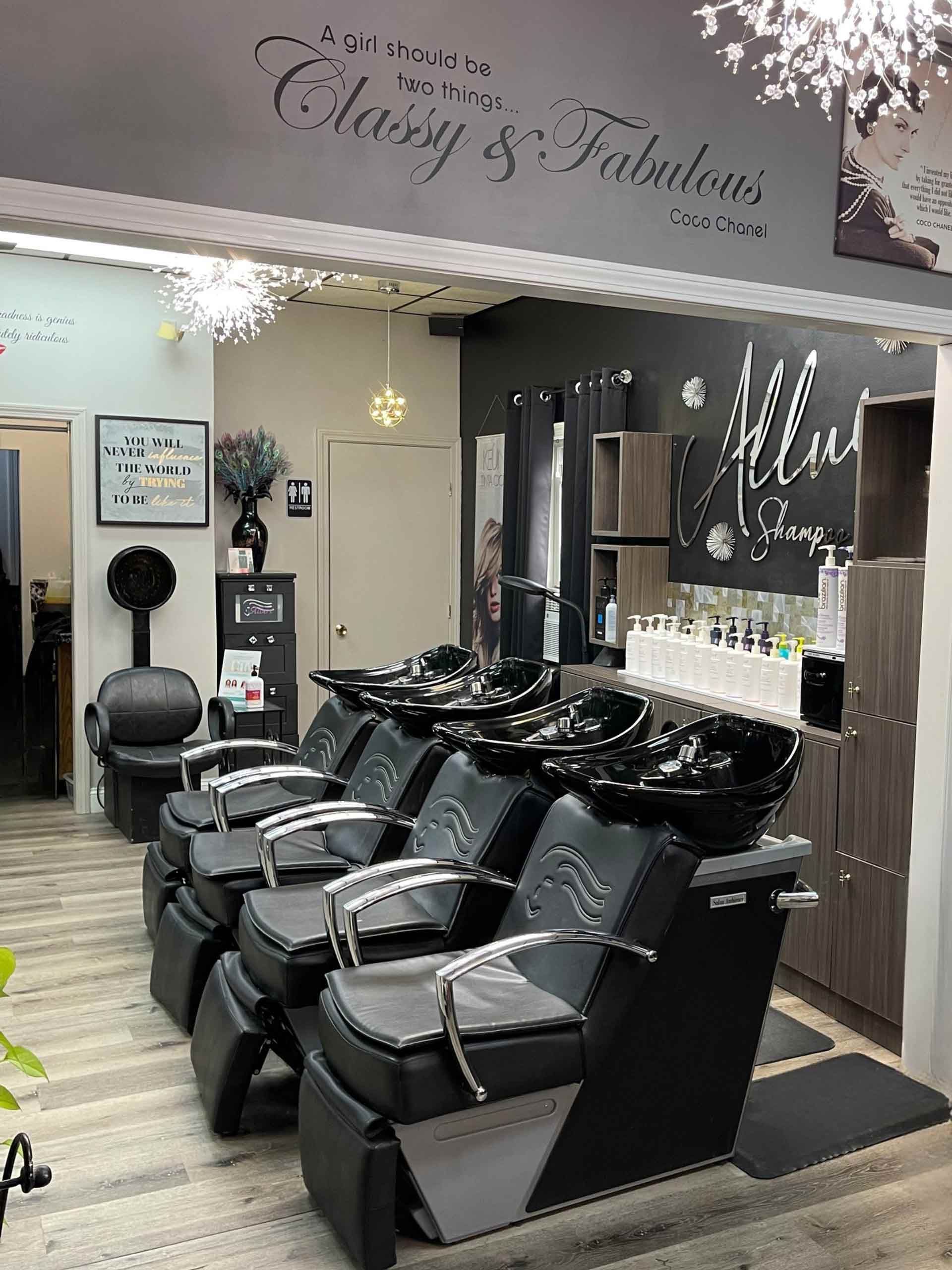 A row of black salon shampoo chairs and wash basins in a hair salon with