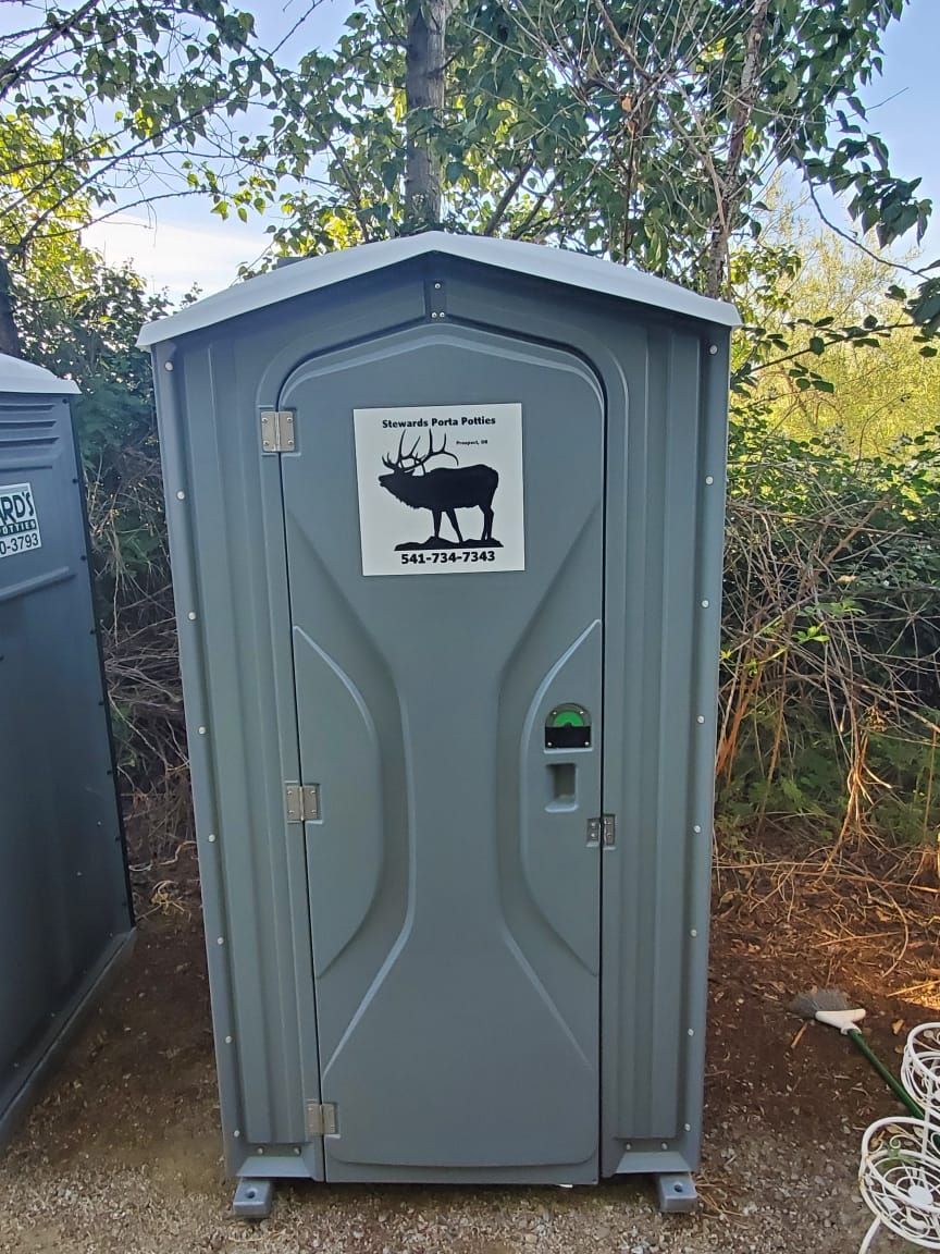 Gray portable toilet with an elk logo, outdoors.