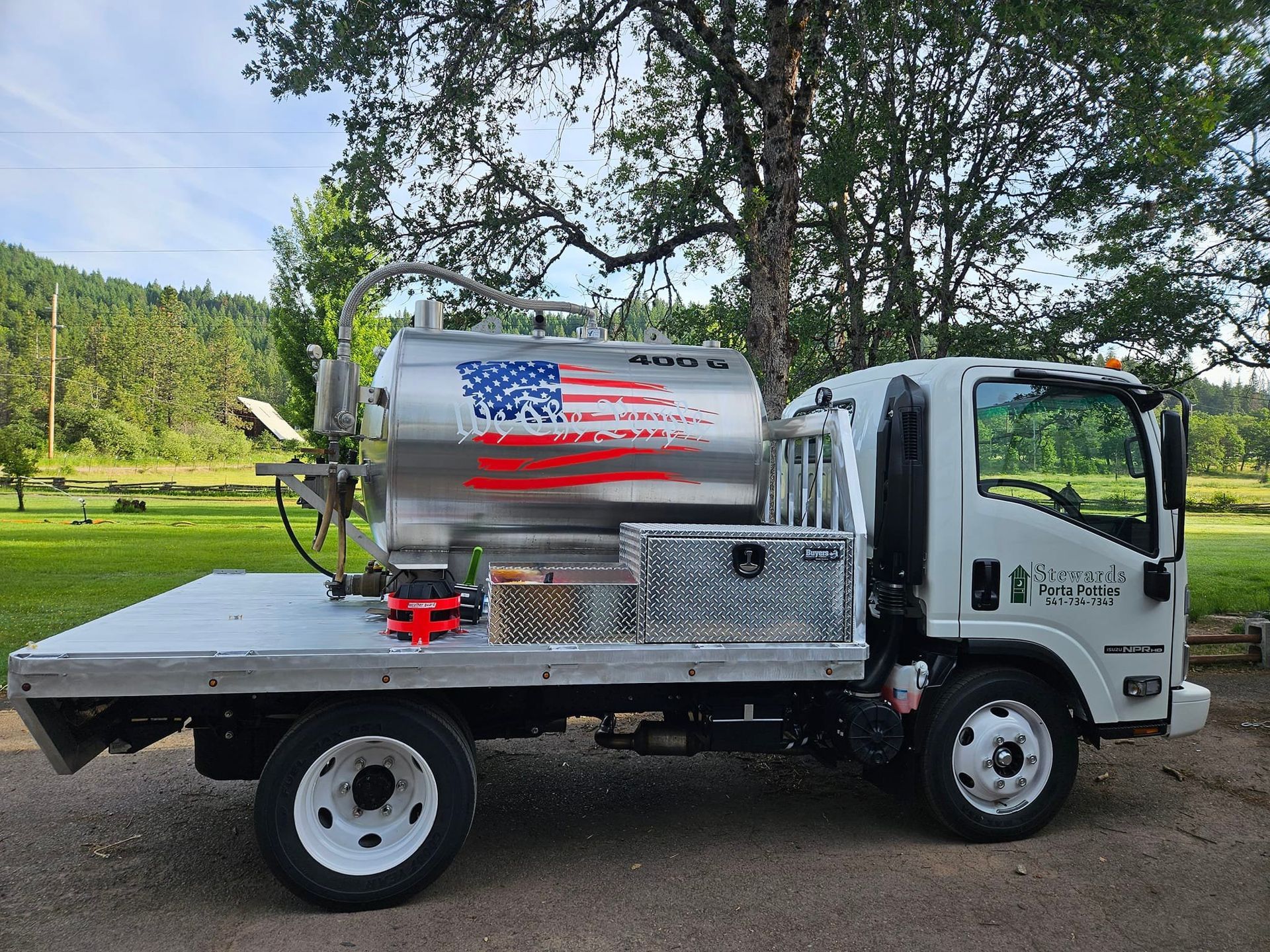 White truck with a silver tank featuring an American flag design parked outdoors.