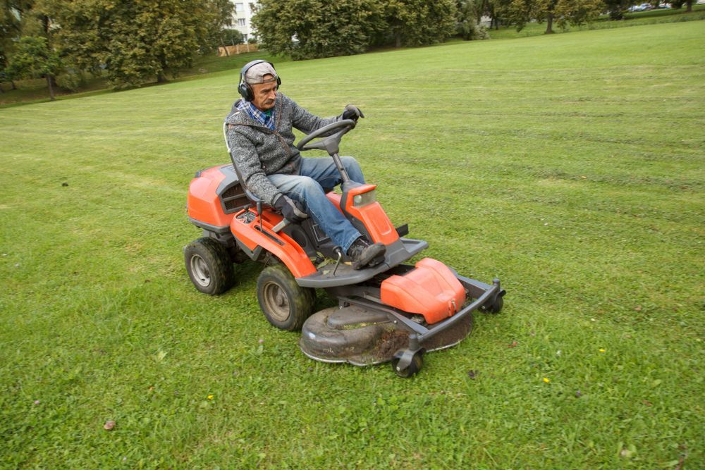 A Yellow Lawn Mower Is Sitting On Top Of A Lush Green Field — Eclipse Hire In Cairns, QLD