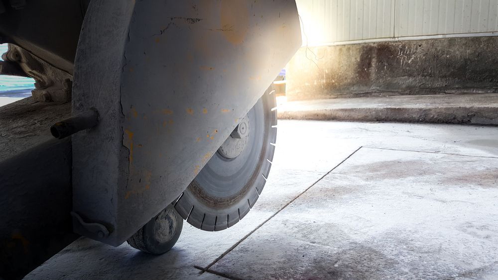 A Person Is Using A Concrete Saw To Cut A Road — Eclipse Hire In  Tablelands, QLD