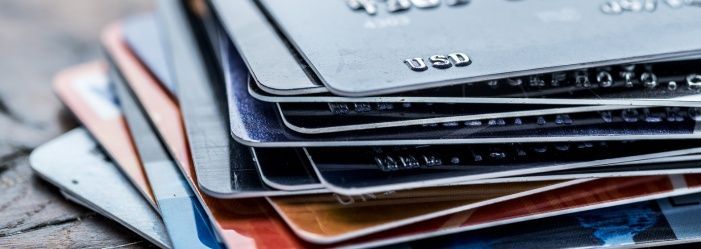 A close-up of a stack of credit cards on a table emphasizes the idea of the pros and cons of having multiple credit cards.