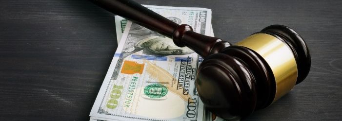 A judge's gavel is sitting on top of a stack of money which indicates the tax penalties and legal consequences
