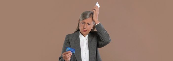 A woman is holding a credit card figuring out on how she will overcome the Debt Addiction