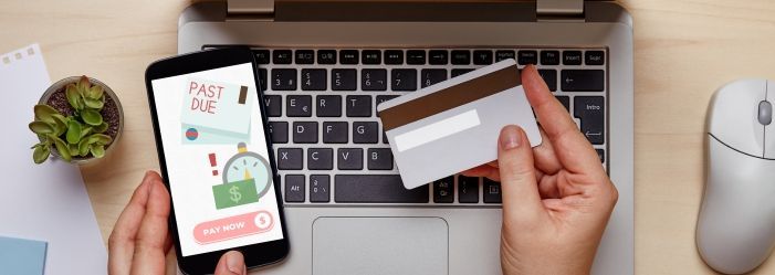 A person is holding a credit card and a cell phone wondering How Late Payments Can Affect Your Credit.