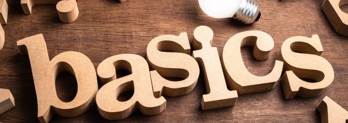 An image of the word basics is written in wooden letters on a wooden table emphasizing the Debt Relief Basics.