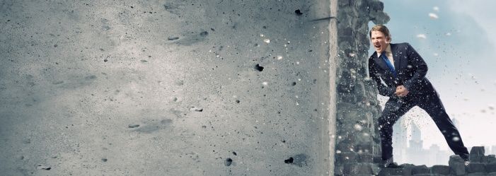 A man in a suit breaking through a concrete wall emphasizes Overcoming Rental Barriers With Poor Credit.