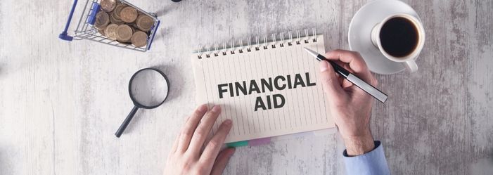 person is writing in a notebook about financial aid.