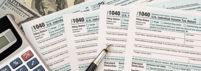 A pen on top of a 1040 tax form next to a calculator and money emphasizing the idea of File Tax Returns
