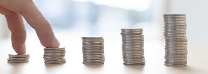 A person stacking coins on top of each other on a table emphasizes the idea of Saving Money and Resetting Financial Habits