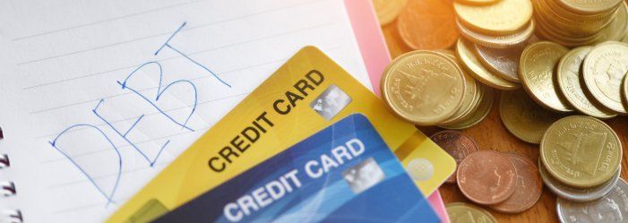 A credit card rests on a notebook beside a stack of coins, symbolizing the journey towards debt relief.