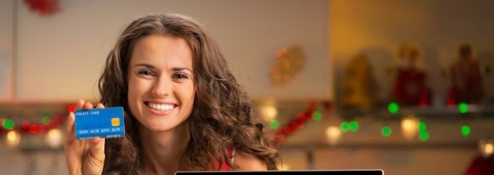 A woman is holding a credit card on a Holiday Season emphasizing the Holiday Credit Card Hacks