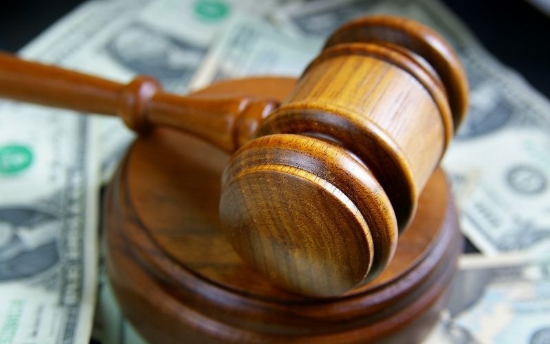 A gavel on top of a pile of money emphasizes the idea How Much Taxes Do You Pay On Laws.