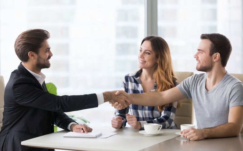 Professional debt settlement consultant shaking hands with the couple, representing Pacific Debt Rel