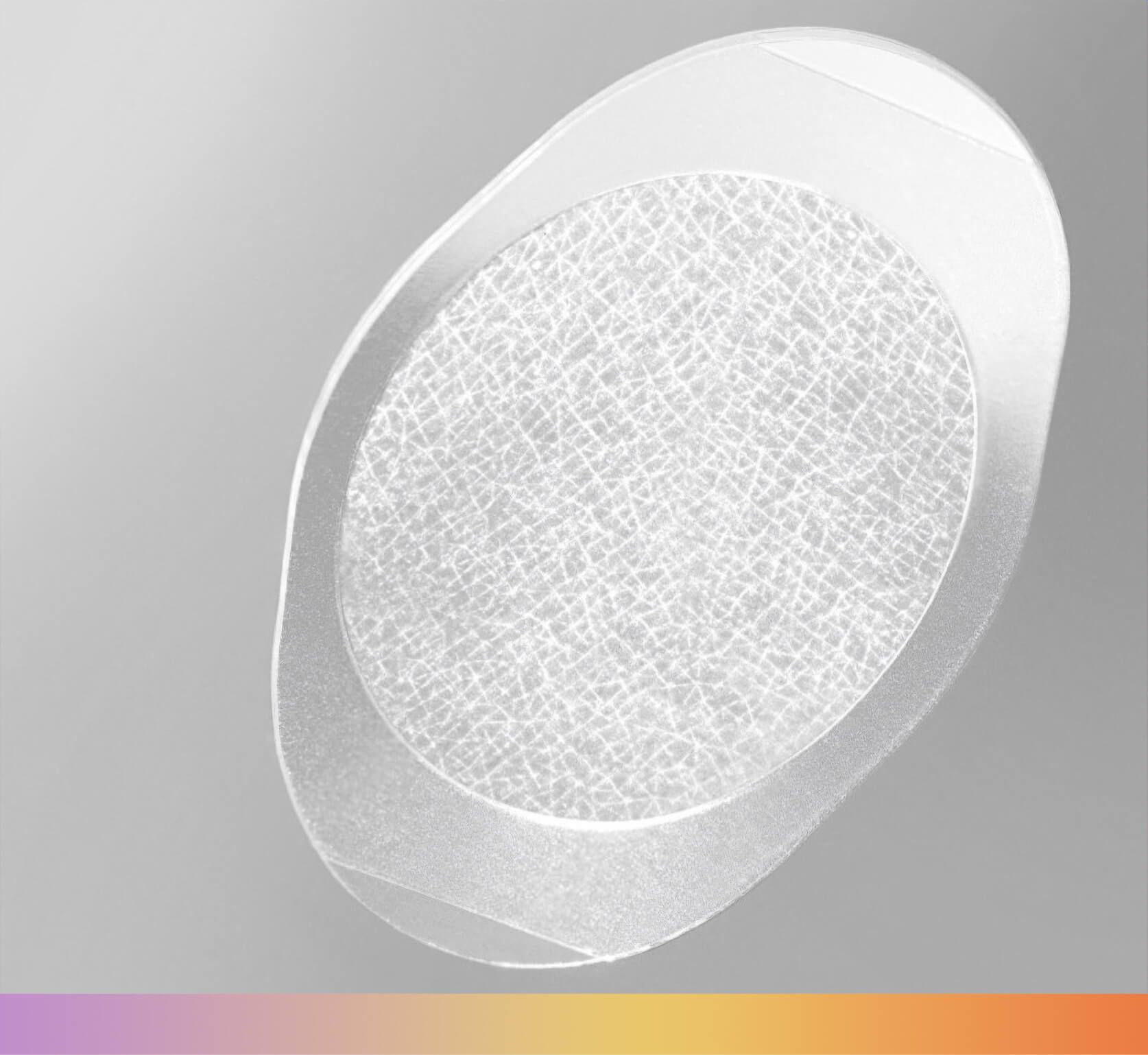 Oval-shaped, white medical wound dressing with central absorbent pad, and clear adhesive border.