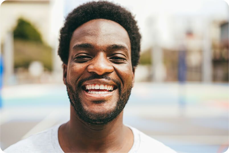 Man with a wide smile, in front of a colorful background.