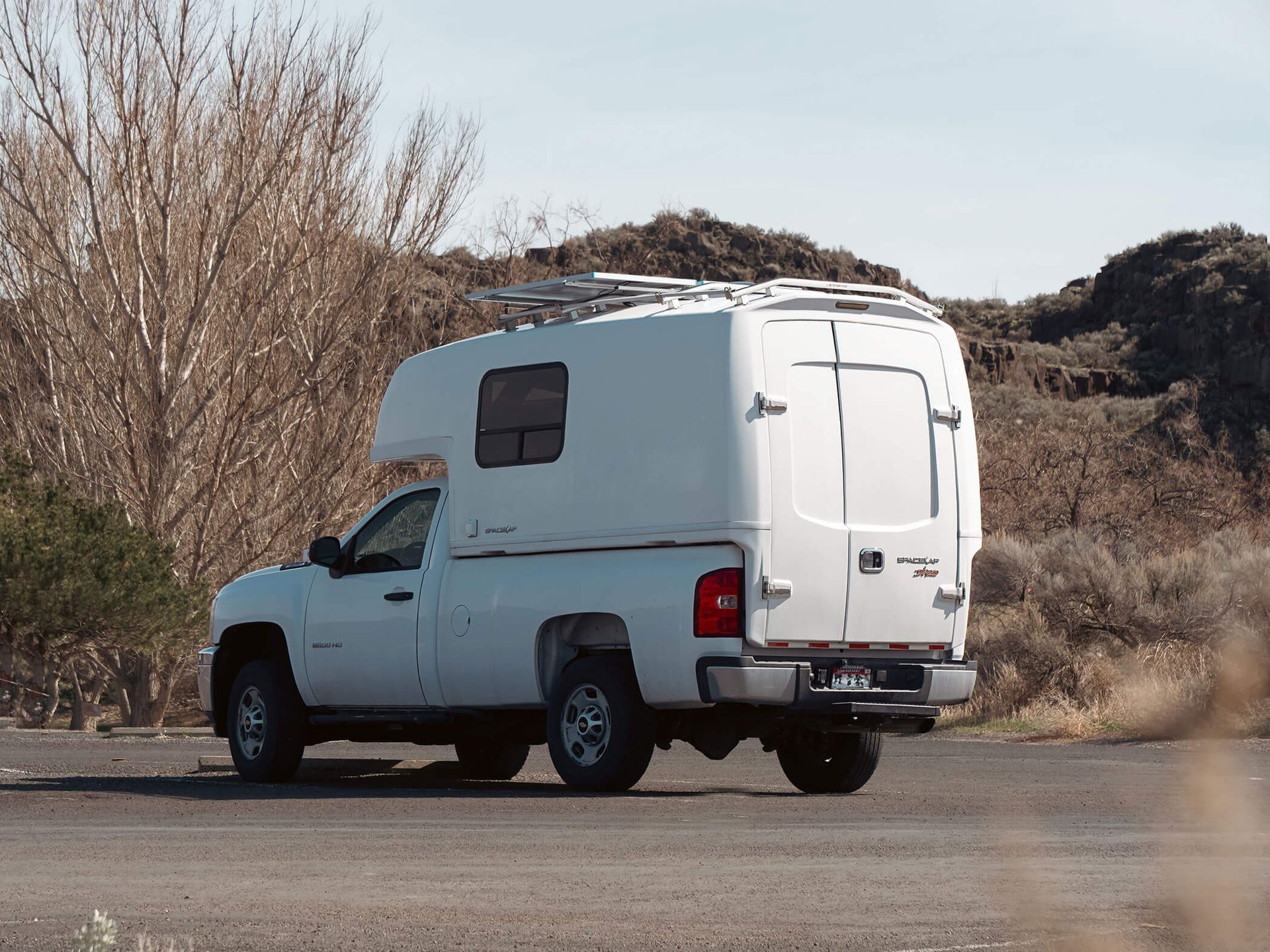 White camper van parked on a roadside near dry shrubs and hills