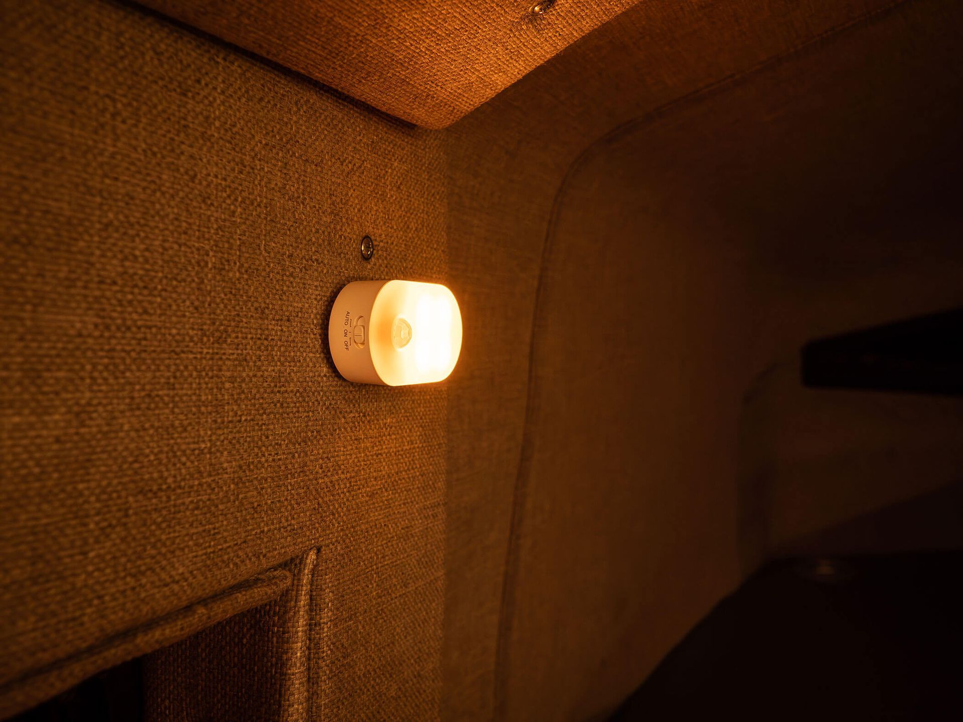 Glowing wall sconce on a textured beige wall in a dim room