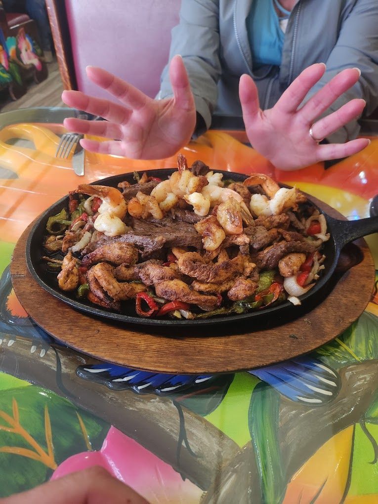 A person is reaching for a plate of food on a table.