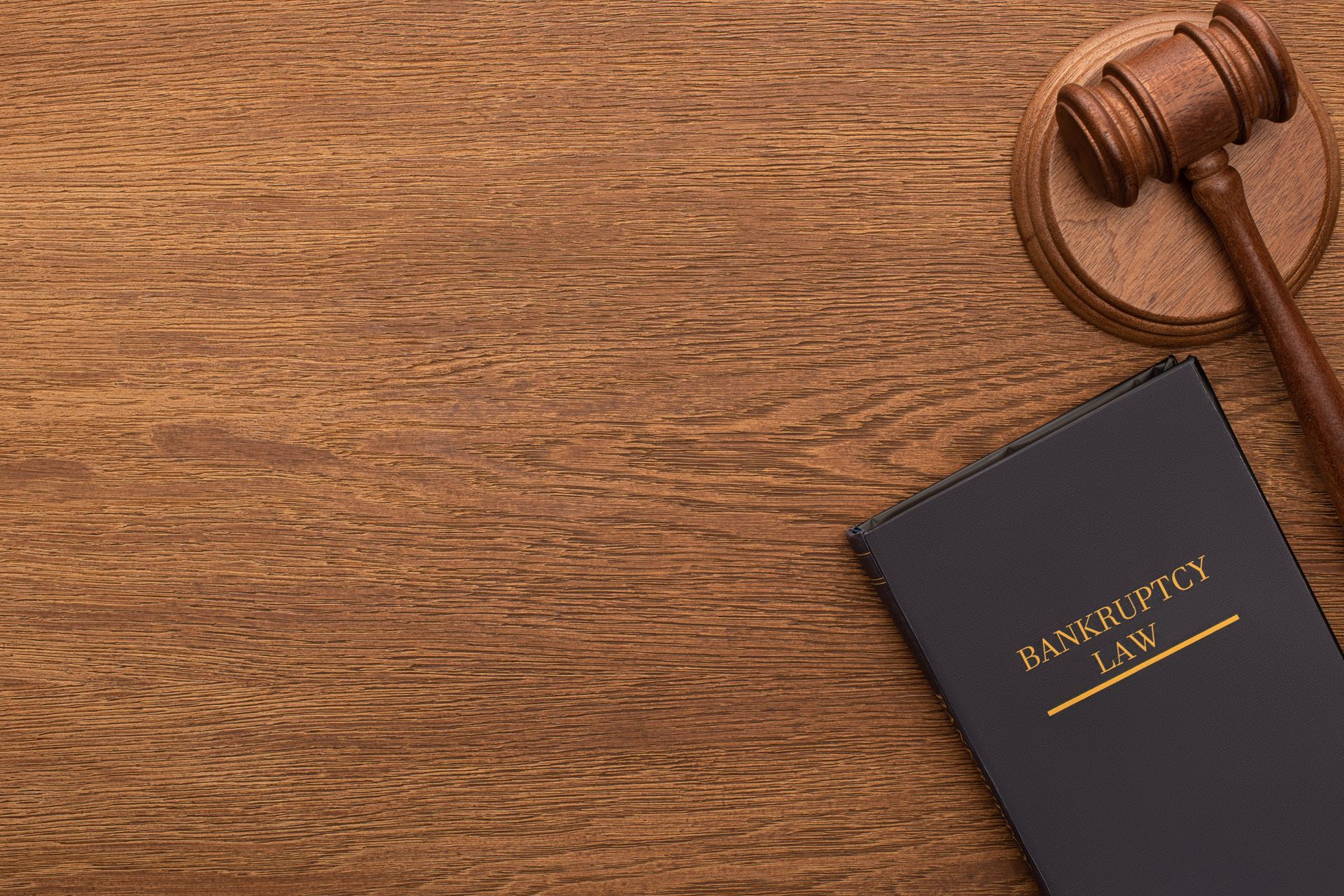 Black bankruptcy law book beside a judge’s gavel on a wooden desk