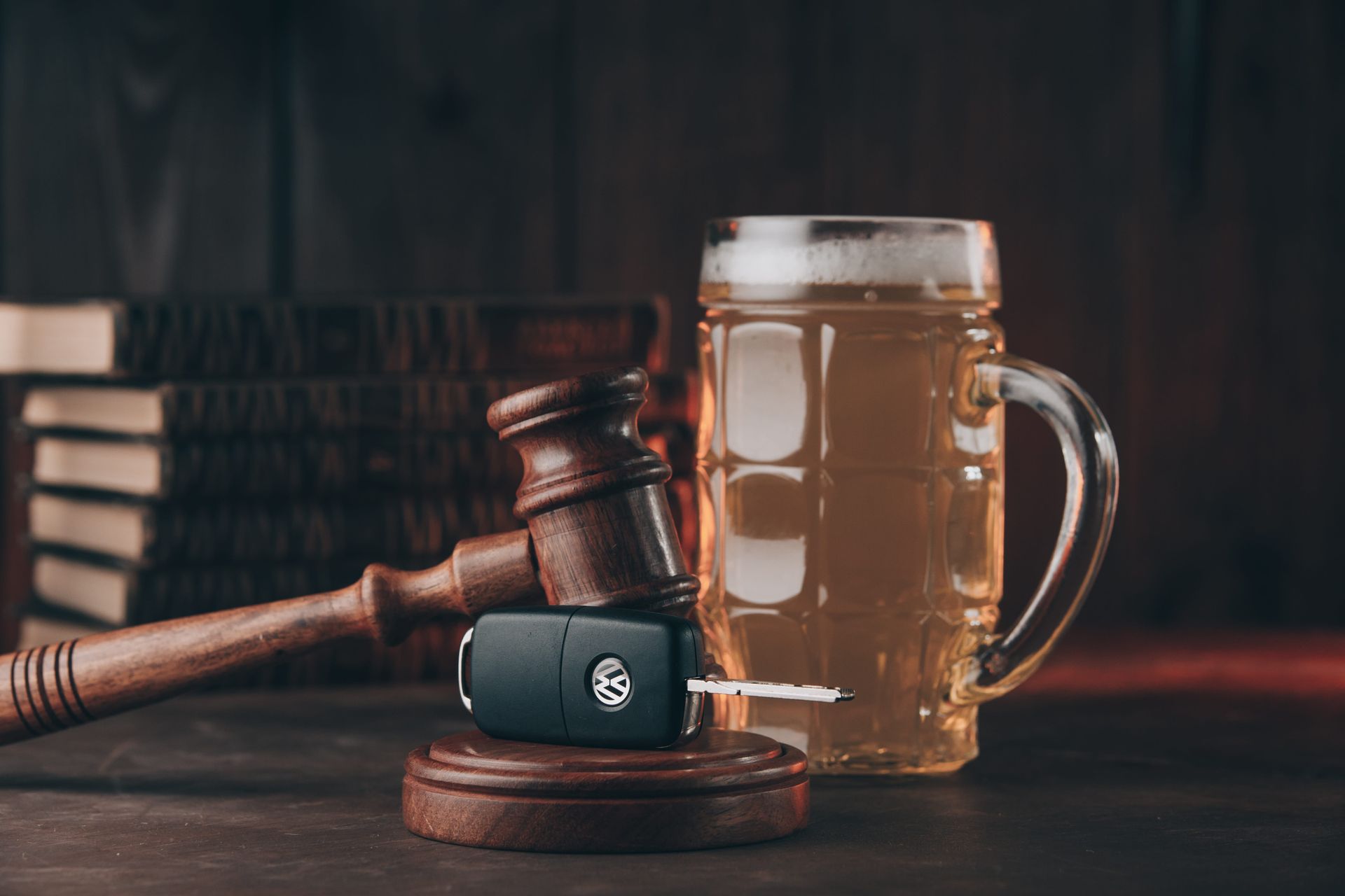 Gavel on a wooden block beside a beer mug and a small black device on a dark desk