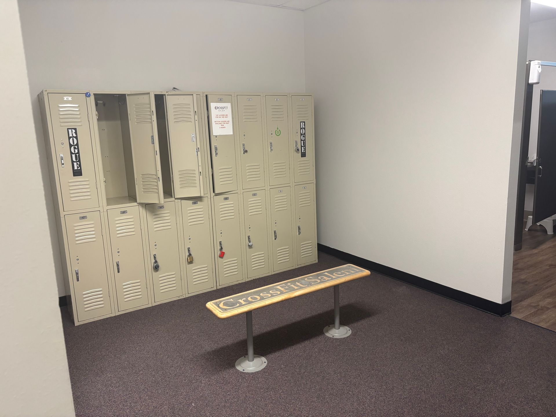 A locker room with lots of lockers and a bench.