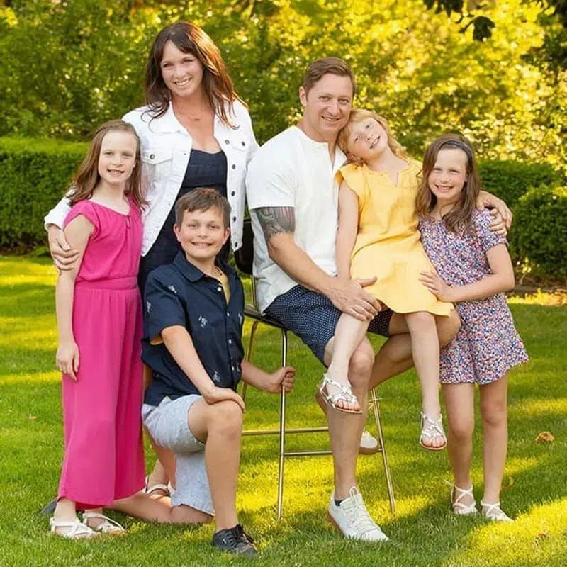 A family is posing for a picture in the grass.