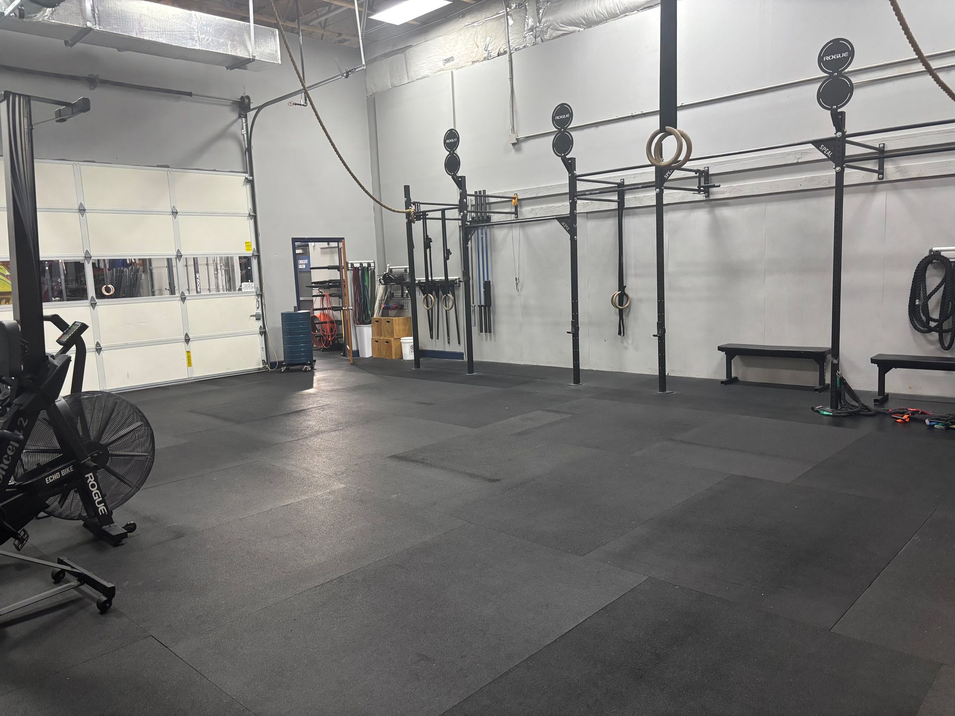 A large empty gym with a bicycle and a fan on the floor.
