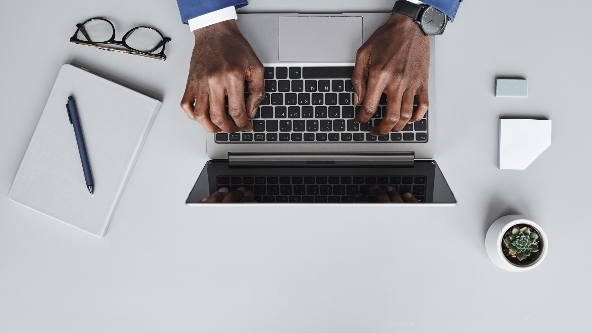 a man is typing on a laptop computer at a desk .