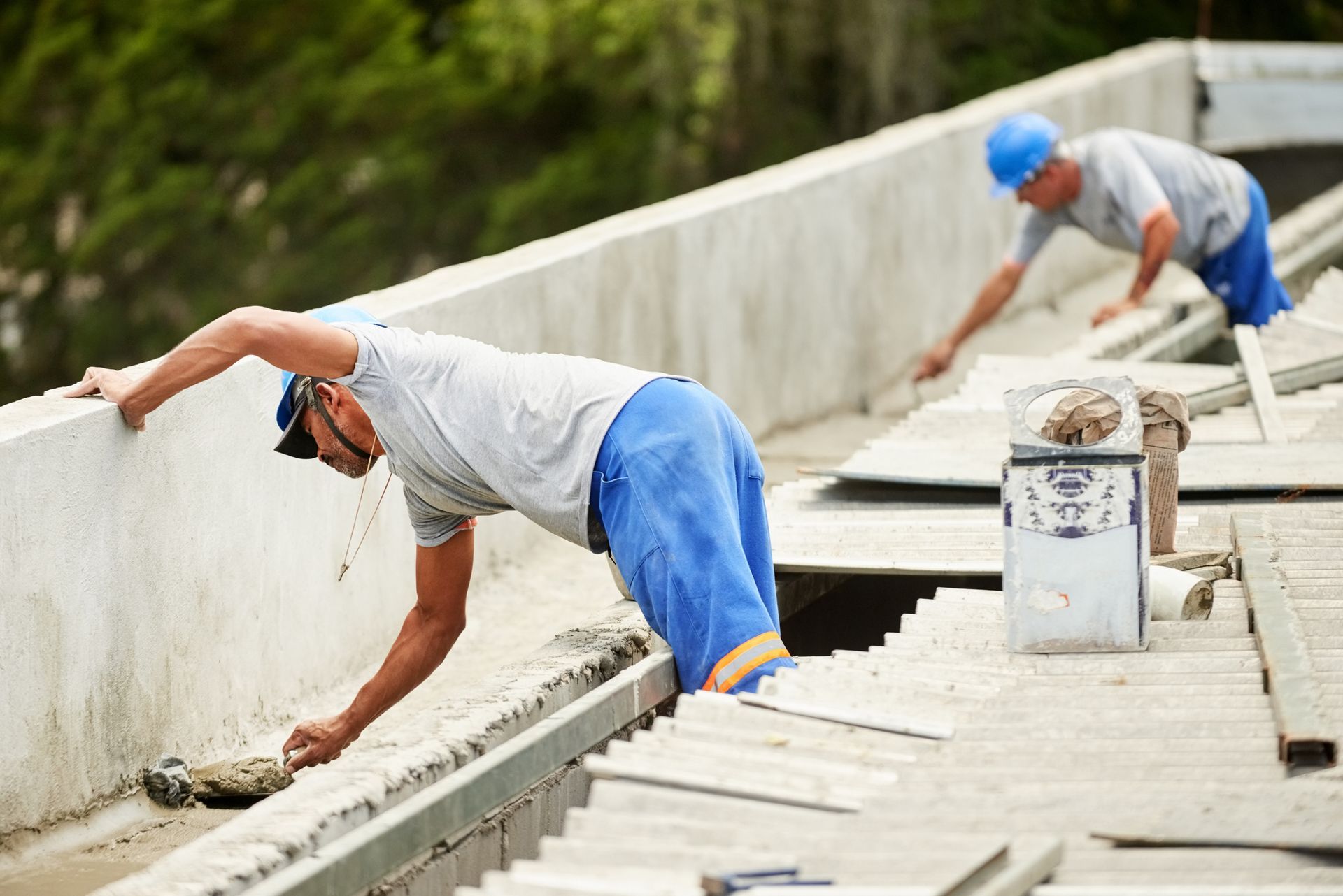 Two construction workers are working on the roof of a building.
