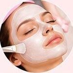 Persona con gli occhi chiusi che riceve un trattamento con maschera facciale applicata con un pennello sulla guancia.