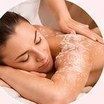 Una donna riceve un massaggio alla schiena con crema bianca su un lettino da spa.