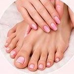 Mani e piedi con unghie curate di rosa pallido su sfondo bianco.