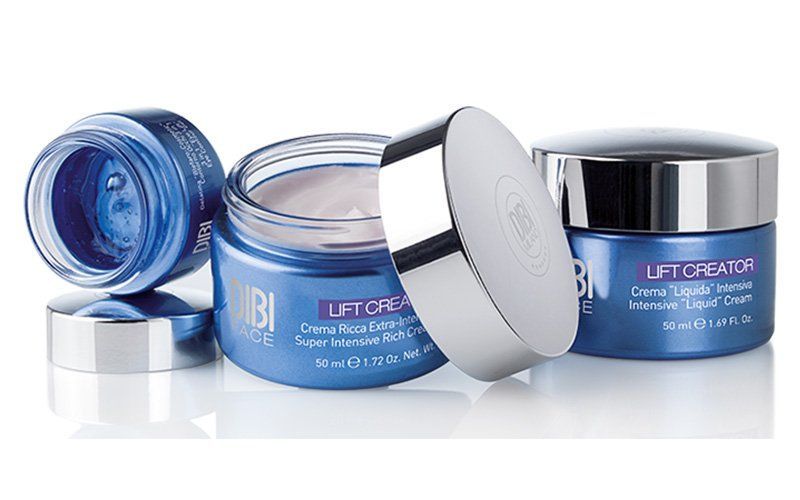Vasetti blu per creme cosmetiche con coperchi argentati, uno aperto per mostrare il prodotto.