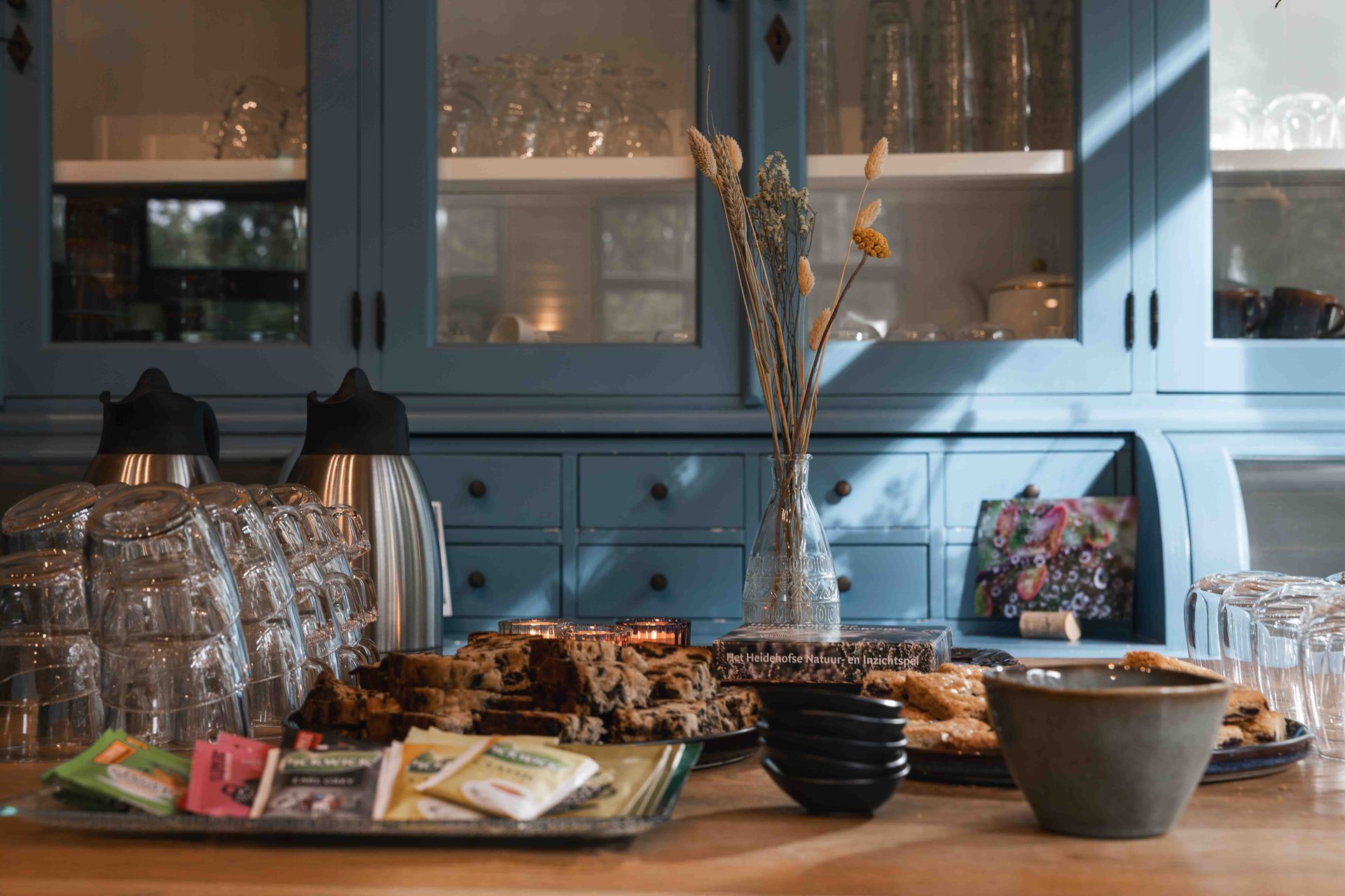 Buffettafel met gebak, snacks en drankjes voor blauwe kasten en een spiegel.