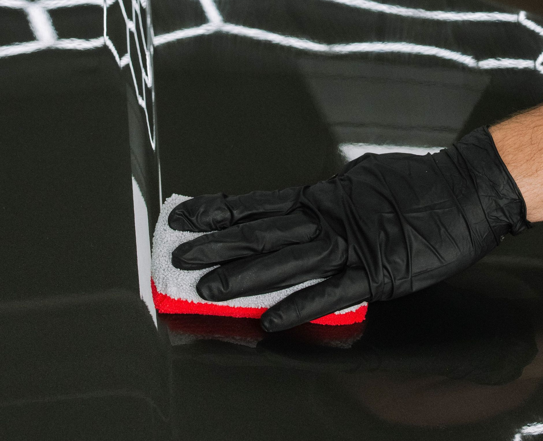 Hand holding a small MAX bottle in front of a green sports car in a driveway.
