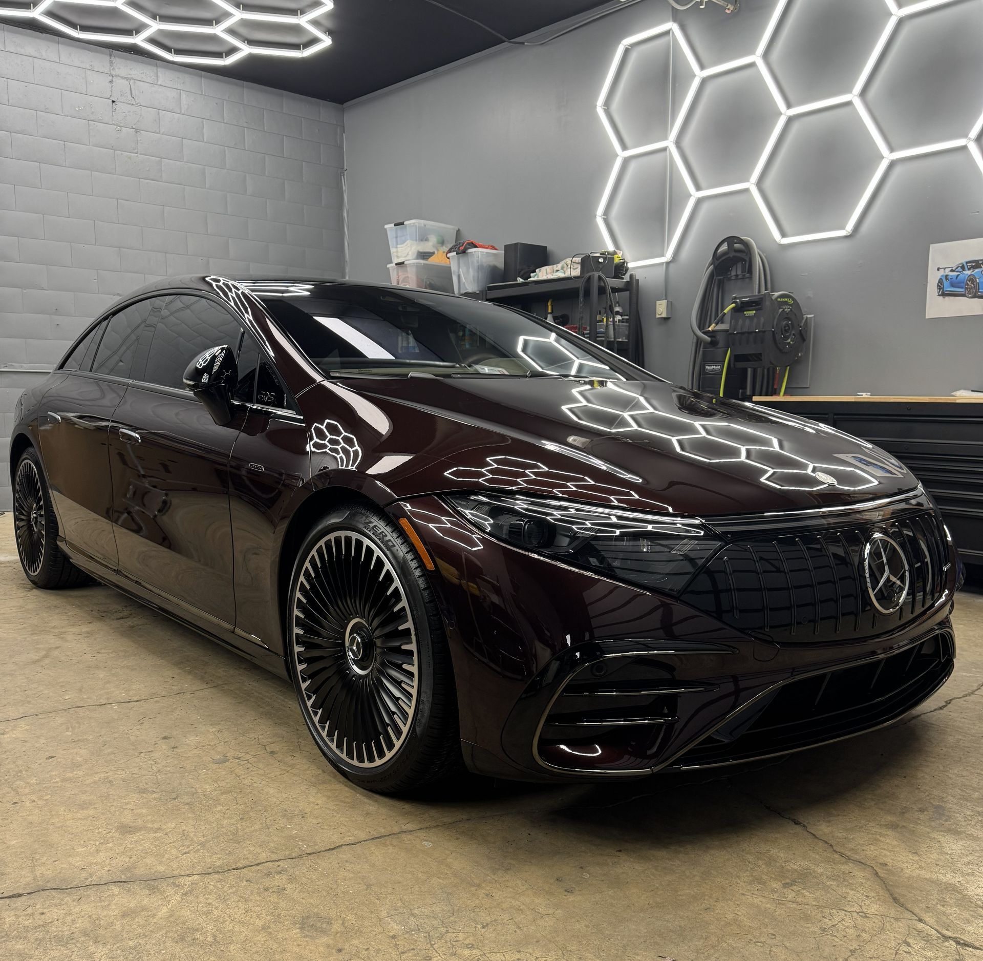 Glossy black Mercedes sedan in a modern garage with hexagonal LED wall lights